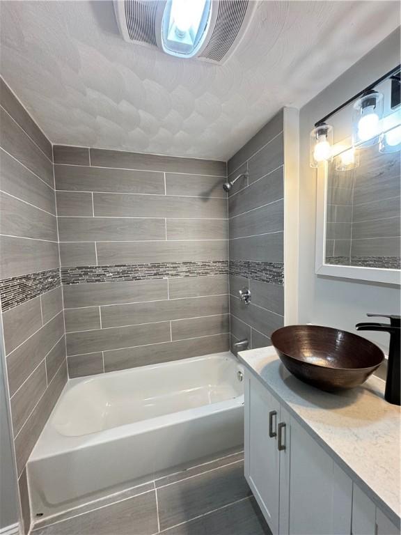 bathroom with tiled shower / bath and vanity