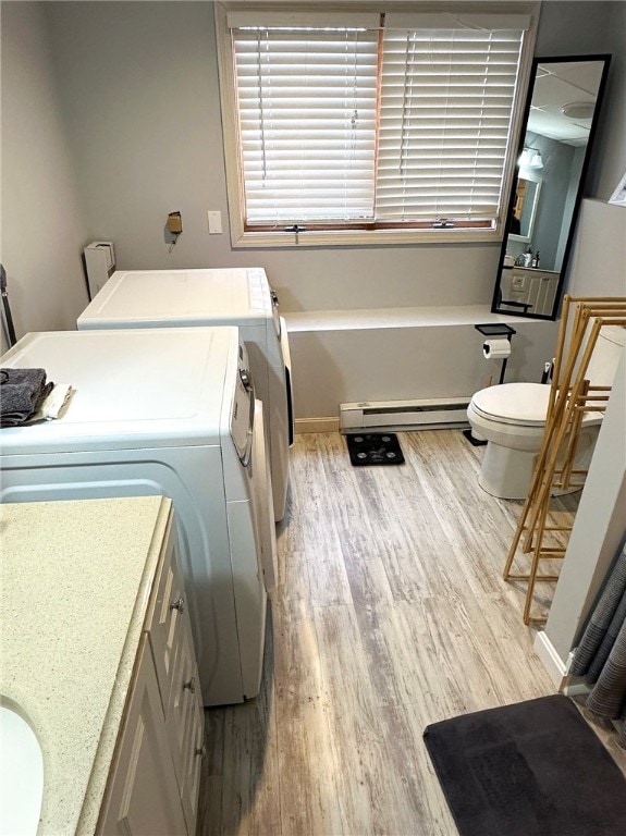 laundry area featuring laundry area, baseboard heating, light wood-type flooring, and washer and dryer