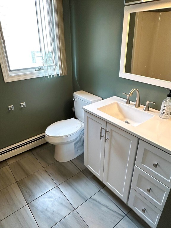 bathroom with baseboard heating, vanity, toilet, and tile patterned floors