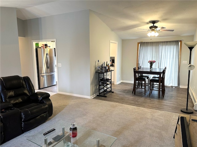 carpeted living area with wood finished floors, vaulted ceiling, baseboards, and ceiling fan