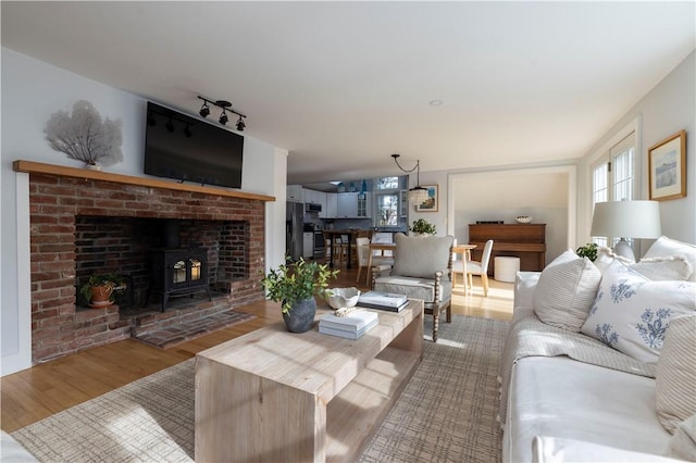 living room with track lighting, light hardwood / wood-style floors, and a wood stove