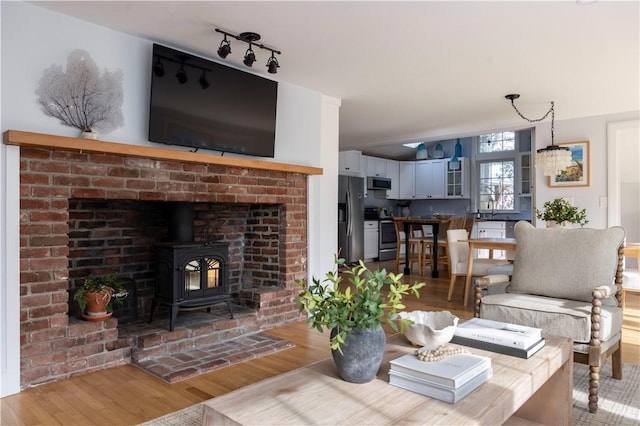 living room featuring lofted ceiling, light hardwood / wood-style floors, and a wood stove