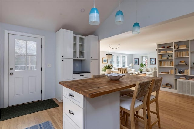 kitchen with hanging light fixtures, white cabinetry, a center island, and butcher block countertops