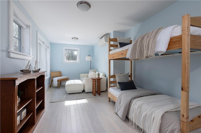 bedroom with light hardwood / wood-style floors and an AC wall unit