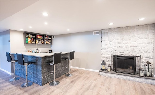 bar with hardwood / wood-style flooring and a fireplace