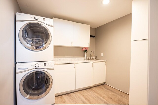 washroom featuring light hardwood / wood-style floors, stacked washer and dryer, cabinets, and sink