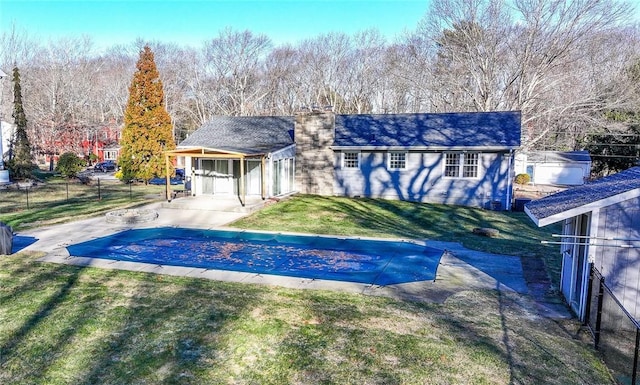 view of front of house with a covered pool, a front yard, and a patio area