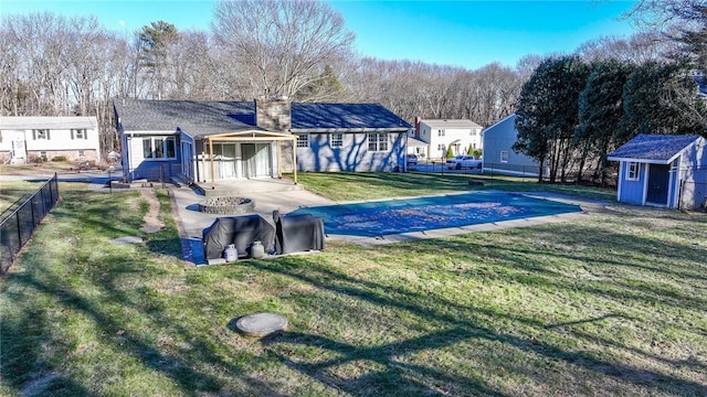 view of pool featuring a storage shed, a patio, a fire pit, and a lawn