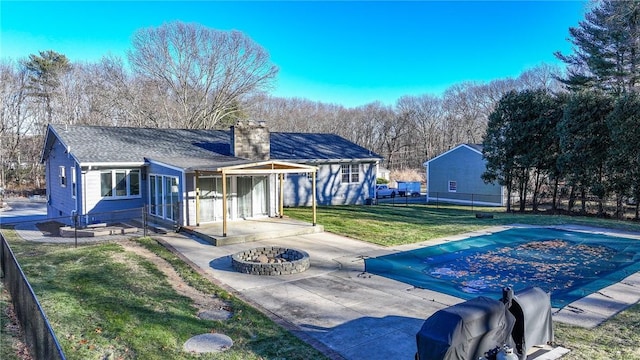 back of house with an outdoor fire pit, a patio, and a lawn