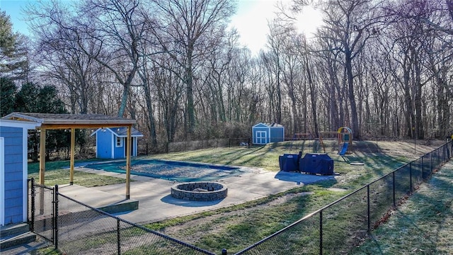 exterior space with a playground, an outdoor fire pit, a yard, and a storage shed