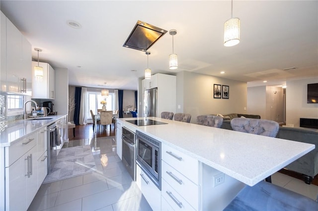 kitchen featuring pendant lighting, a kitchen island, stainless steel appliances, white cabinets, and a kitchen bar