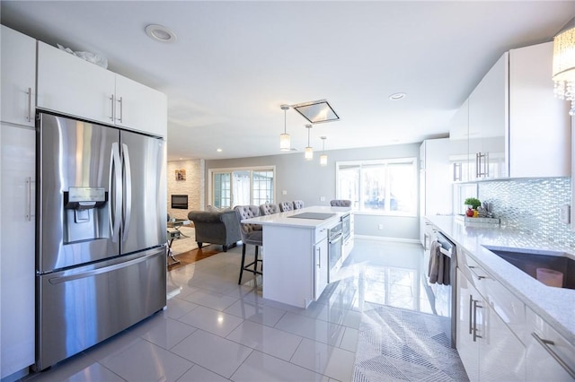 kitchen with stainless steel appliances, a breakfast bar, hanging light fixtures, and white cabinets