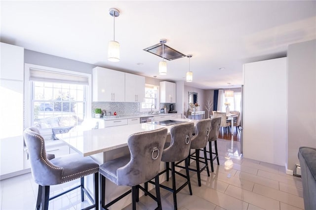 kitchen featuring a breakfast bar, pendant lighting, white cabinetry, sink, and decorative backsplash