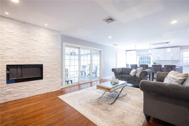 living room with hardwood / wood-style floors and a stone fireplace