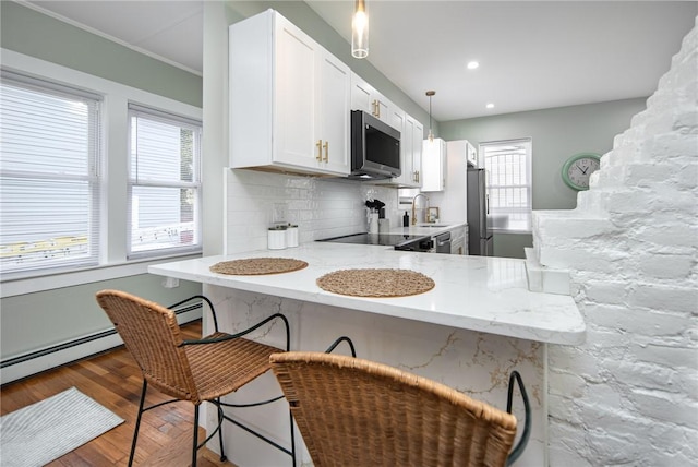 kitchen featuring pendant lighting, appliances with stainless steel finishes, a kitchen breakfast bar, white cabinets, and kitchen peninsula