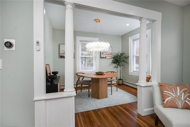 dining space featuring a baseboard heating unit, dark wood-type flooring, plenty of natural light, and ornate columns