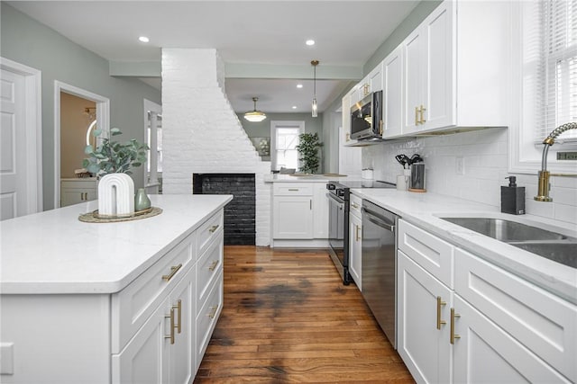 kitchen featuring sink, dark wood-type flooring, appliances with stainless steel finishes, white cabinets, and a kitchen island