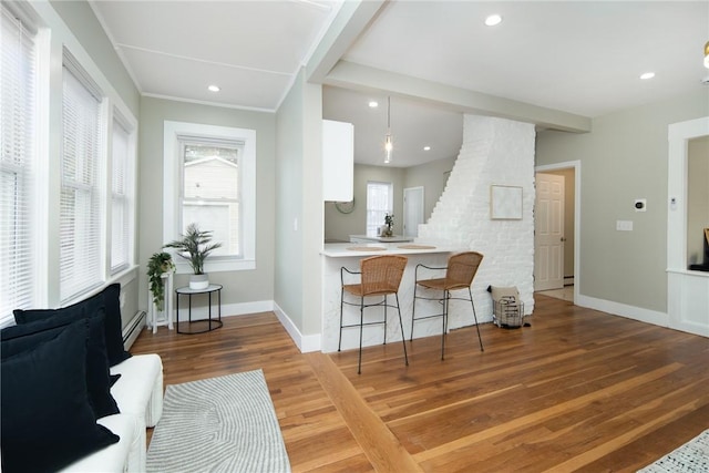 kitchen featuring pendant lighting, wood-type flooring, white cabinets, a baseboard heating unit, and kitchen peninsula