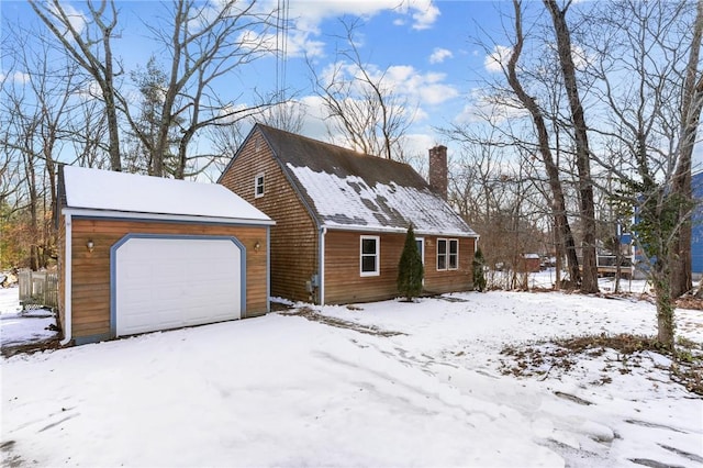 view of snow covered exterior featuring a garage and an outdoor structure