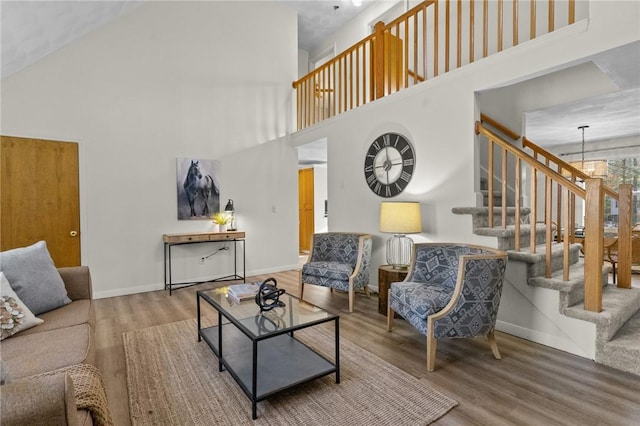 living room featuring an inviting chandelier, hardwood / wood-style flooring, and a towering ceiling