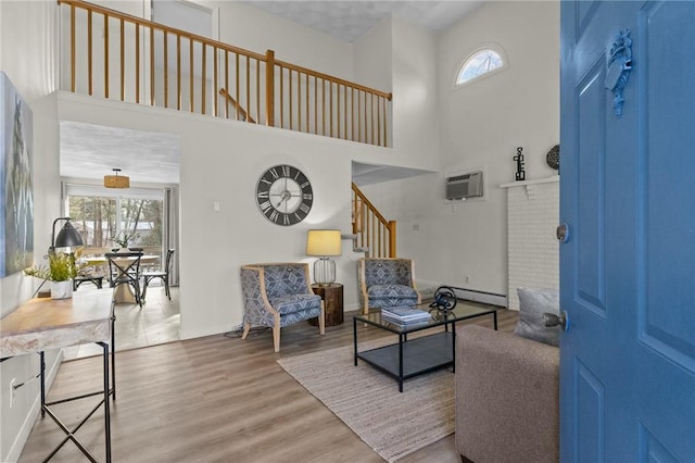 living room with wood-type flooring, a wall unit AC, a healthy amount of sunlight, and a high ceiling