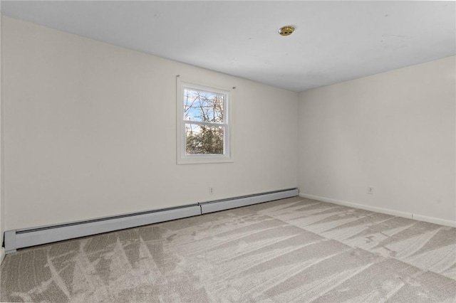 empty room featuring a baseboard heating unit and light colored carpet