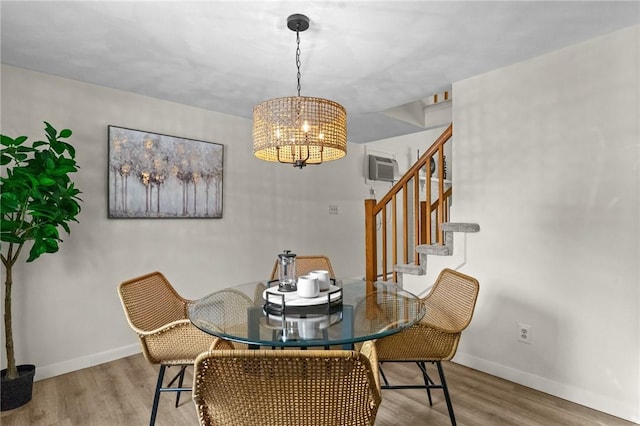 dining area with a wall mounted AC, a notable chandelier, and light wood-type flooring