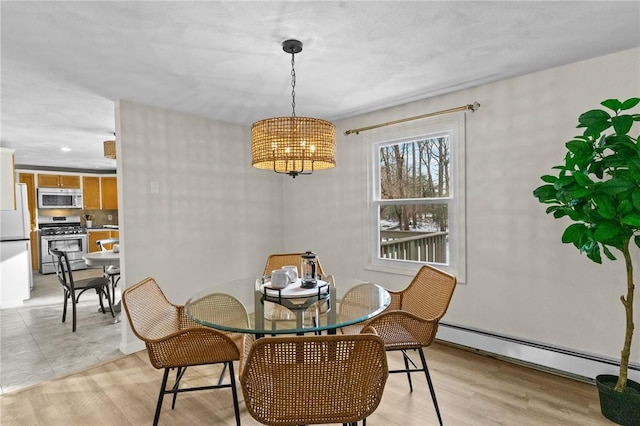 dining space with a baseboard heating unit and light wood-type flooring