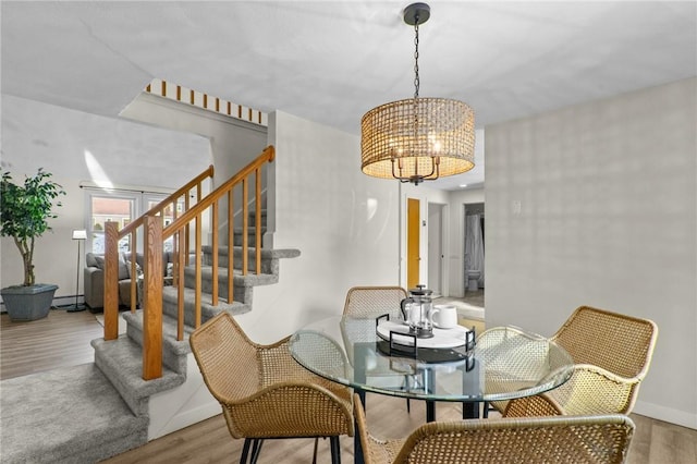 dining space with baseboard heating, a chandelier, and light hardwood / wood-style flooring