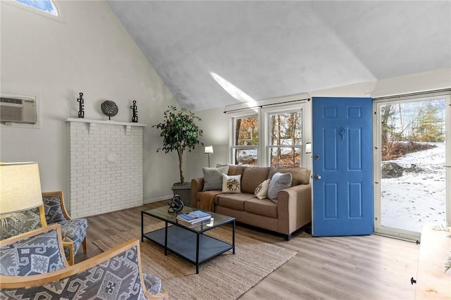 living room with lofted ceiling, hardwood / wood-style floors, and an AC wall unit