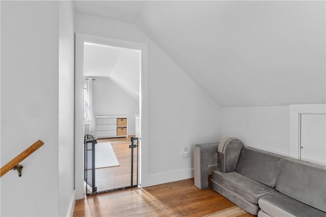 living area with lofted ceiling, baseboards, and light wood-style floors