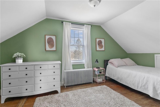 bedroom with dark hardwood / wood-style flooring, radiator heating unit, and lofted ceiling