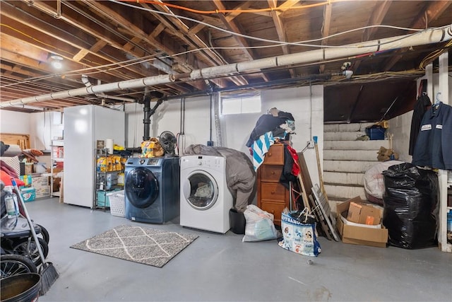 basement featuring washing machine and dryer and white refrigerator