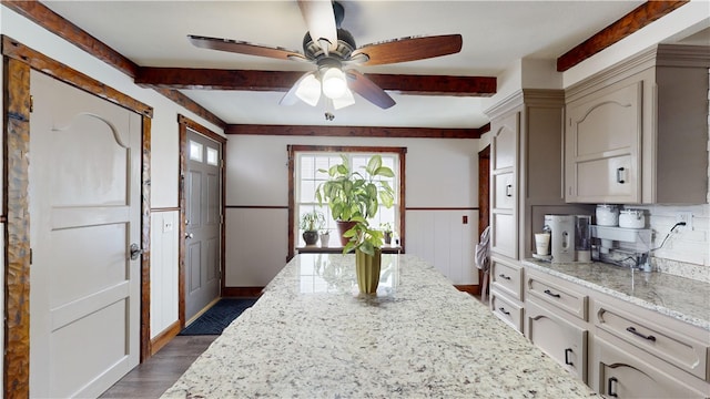 kitchen featuring beam ceiling, dark wood-type flooring, light stone countertops, and ceiling fan