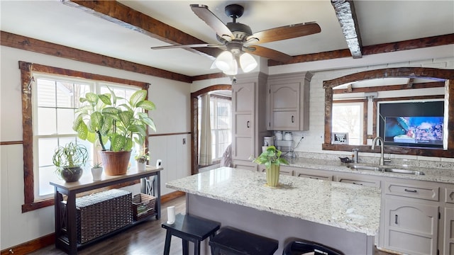 kitchen featuring sink, beam ceiling, gray cabinets, and a healthy amount of sunlight