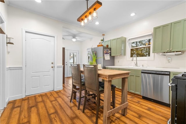 kitchen with sink, green cabinets, hanging light fixtures, and appliances with stainless steel finishes