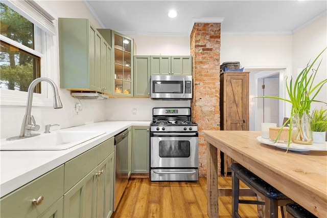 kitchen featuring crown molding, green cabinetry, stainless steel appliances, and sink