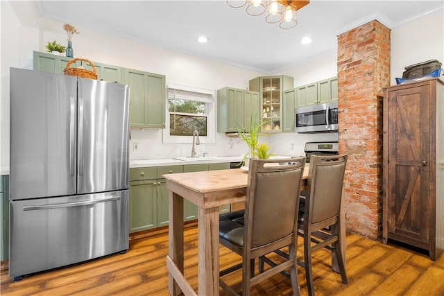 kitchen with appliances with stainless steel finishes, sink, hardwood / wood-style floors, and green cabinetry