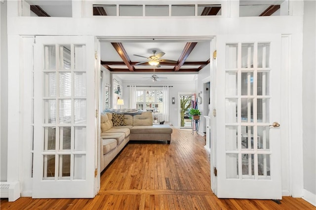 unfurnished living room featuring beam ceiling, coffered ceiling, ceiling fan, and light hardwood / wood-style flooring