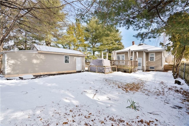 snow covered back of property with a wooden deck