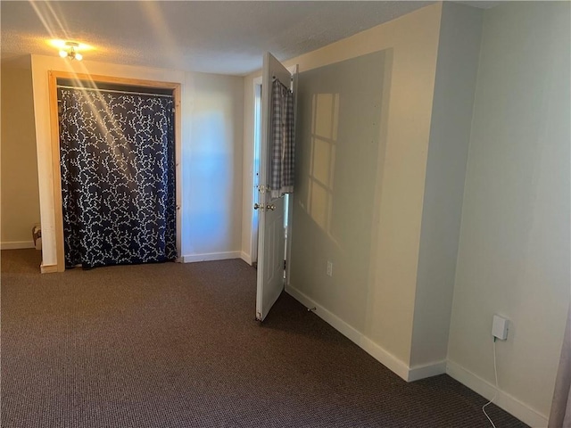 unfurnished room featuring dark colored carpet