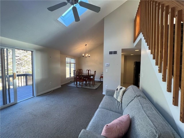 carpeted living room with ceiling fan with notable chandelier, high vaulted ceiling, and a skylight