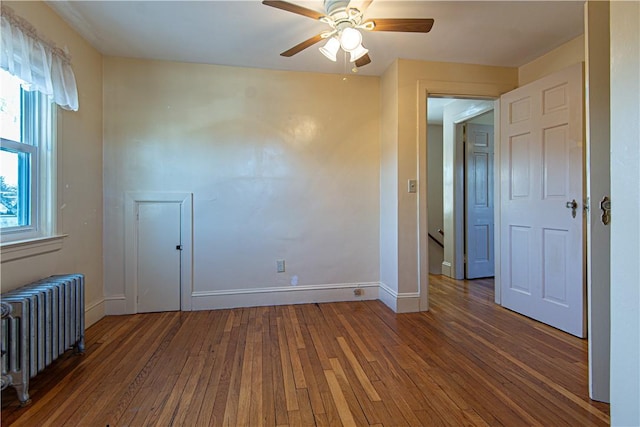 unfurnished room featuring radiator heating unit, dark hardwood / wood-style floors, and ceiling fan