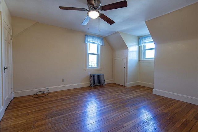 additional living space featuring radiator heating unit, dark hardwood / wood-style floors, ceiling fan, and vaulted ceiling