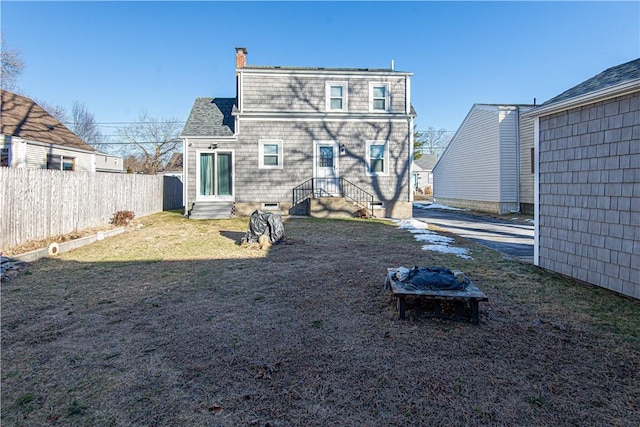 rear view of property with an outdoor fire pit and a yard