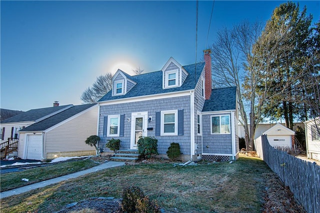 cape cod-style house featuring an outbuilding, a garage, and a front yard