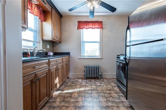 kitchen with sink, stainless steel fridge, black range with gas cooktop, backsplash, and radiator heating unit