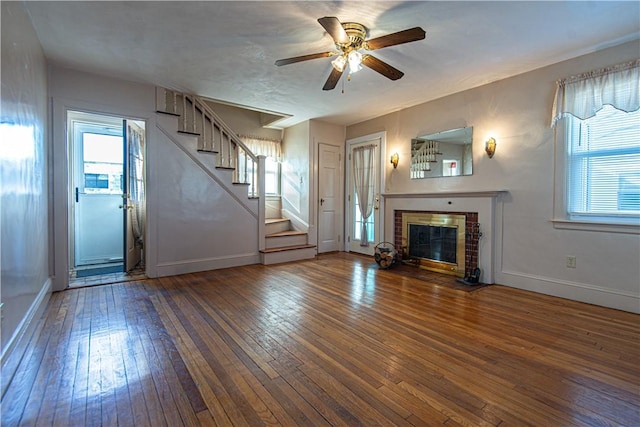 unfurnished living room featuring ceiling fan, dark hardwood / wood-style flooring, and a brick fireplace