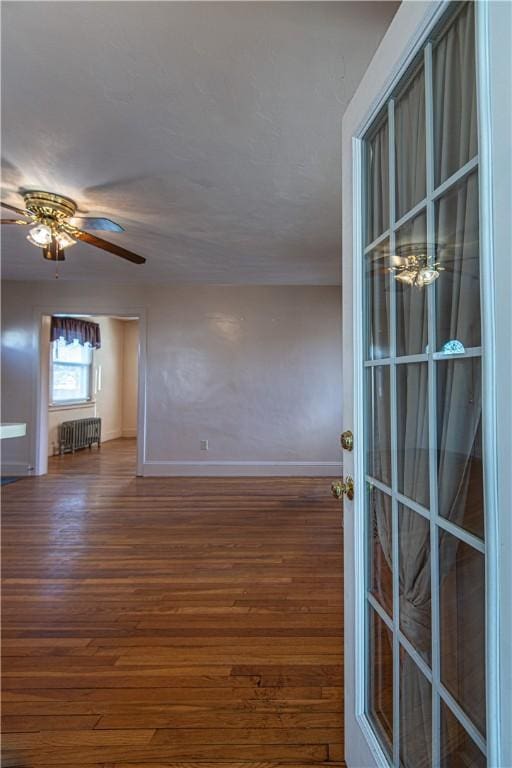 spare room with dark hardwood / wood-style floors, radiator heating unit, and ceiling fan