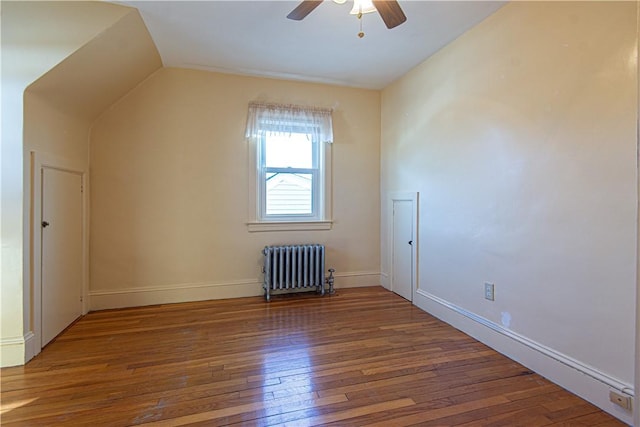 additional living space with wood-type flooring, vaulted ceiling, radiator heating unit, and ceiling fan